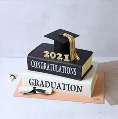 a graduation cake made to look like books with the number twenty on top and congratulations written in gold