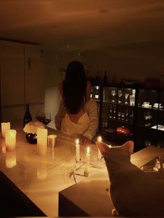 a woman sitting at a counter with candles in front of her and a cat on the counter