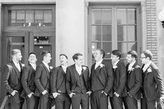 a group of young men standing next to each other in front of a tall building