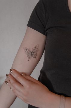 a woman's arm with a butterfly tattoo on the left side of her arm