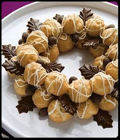 a white plate topped with cookies covered in icing and chocolate leaves on top of it