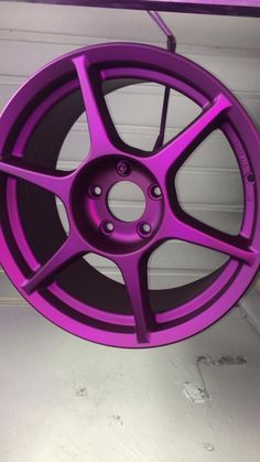 a purple wheel hanging from the side of a garage door in front of a white wall