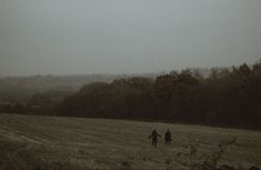 two people walking through a field in the rain