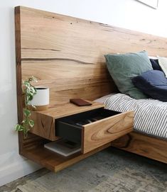 a bed with a wooden headboard and drawers on the bottom shelf, next to a potted plant