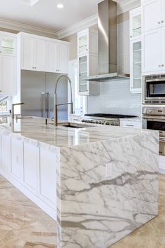 a large kitchen with marble counter tops and white cabinets, along with stainless steel appliances