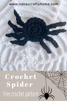 a crochet spider sitting on top of a white blanket next to a black spider web