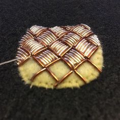 a piece of metal wire sitting on top of a black surface next to a thread