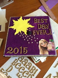 a purple and gold graduation cap with the words best day ever on it, surrounded by cut outs