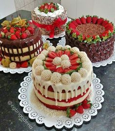 four cakes with strawberries and chocolate on top