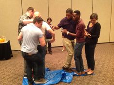 a group of people standing around each other in a room with blue tarp on the floor