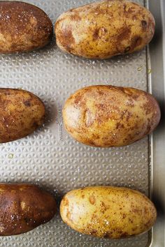 four potatoes sitting on top of a metal pan