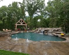 an outdoor pool with waterfall and seating area