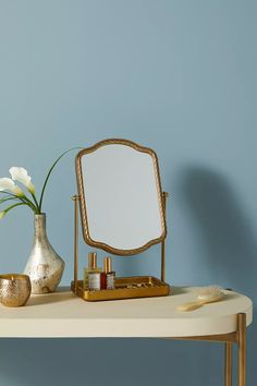 a table with a mirror, vase and other items on it