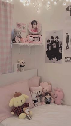 there are many stuffed animals on the bed in this small child's room with pink and white decor