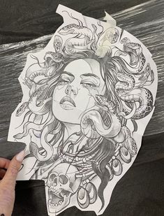 a woman's face is drawn on a piece of paper with skulls around her