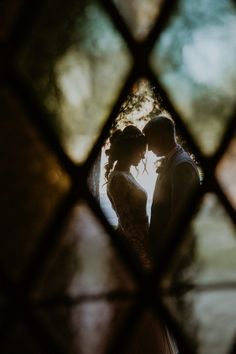 a bride and groom standing in front of a stained glass window with the sun shining through it