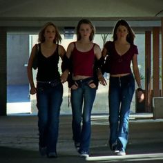 three women walking down the street in jeans and red tops with their arms around each other