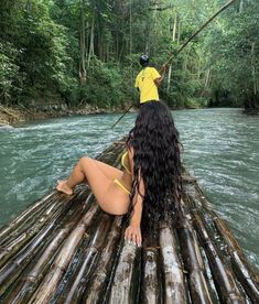 a woman in a yellow bathing suit is sitting on a bamboo raft over the water