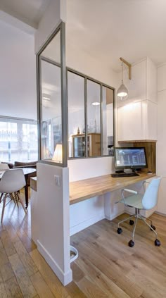 a room with a desk, chairs and a computer monitor on top of the table