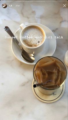 there is a cup of coffee and a spoon on the table with two cups next to each other