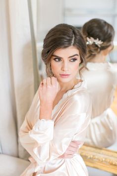 a woman in a wedding dress looking at herself in the mirror with her hand on her chin