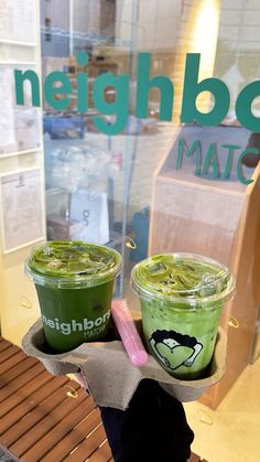 two cups of green tea sit in front of a store window with the words neighborhood match written on it