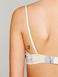 the back of a woman's bra with tattoos on her left shoulder and chest