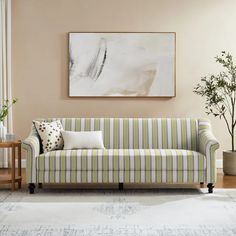 a living room with a striped couch and potted plant