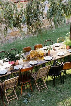 an outdoor dining table set up with plates and place settings for six people, surrounded by greenery