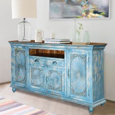 a blue painted buffet table in a living room with a painting on the wall behind it