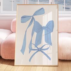 a blue bow is hanging on the wall next to a pink couch in front of a window