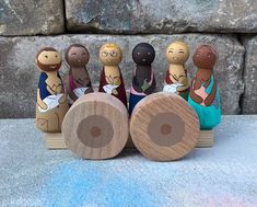 a group of wooden dolls sitting next to each other on top of a stone wall