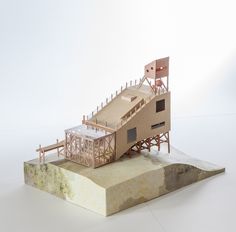 a model of a building made out of wood and paper on top of a block of concrete