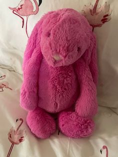 a pink teddy bear sitting on top of a bed