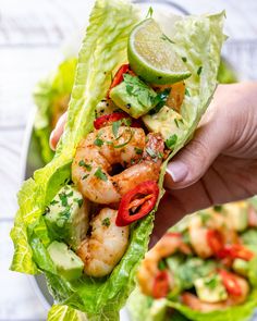 a person is holding up a lettuce wrap with shrimp and avocado