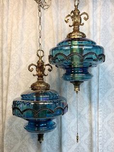 two blue glass lamps hanging from a ceiling