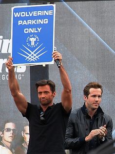 two men holding up a blue sign that says wolverine parking only in front of them