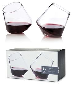 two glasses filled with red wine sitting on top of a white box next to each other