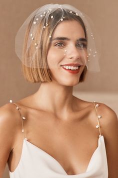 a woman wearing a veil with pearls on it