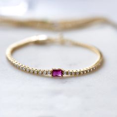 Super chic tennis bracelet with a ruby baguette charm, that is beautiful and elegant! Adds a nice touch of sparkle! Looks like real diamonds! We use a Thick plating of 14k Gold or Rhodium over brass Available in Sizes: 6.5" or 7" 2mm Thickness 4x6mm Baguette Stone Latch Closure Nickel-free, lead free and hypoallergenic Highest Grade CZ for an authentic diamond look Available in Diamond, Sapphire, or Emerald Ruby Jewelry With Baguette Diamonds As Gift, Fine Jewelry Baguette Tennis Bracelet Gift, Recycled Metal, Tennis Bracelet, Real Diamonds, Timeless Pieces, Precious Metals, Baguette, Silver Gold