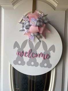 a welcome sign on the front door of a house with bunny ears and bows attached to it