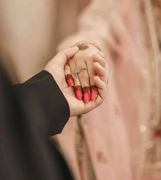 a man and woman holding each other's hand with their wedding rings on them