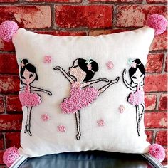 two ballerinas on a white pillow with pink pom - poms hanging from the back