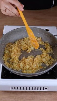 a person stirring food in a pan on top of a stove