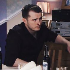 a man sitting at a table with bottles and glasses