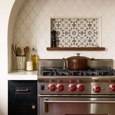 a stove top oven sitting inside of a kitchen next to a wall with pictures on it