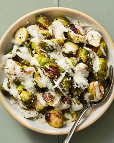 a bowl filled with brussel sprouts covered in white sauce and cheese