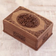 an intricately carved wooden box sits on a white tableclothed surface, with the lid partially closed