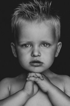 a black and white photo of a young boy with his hands folded over his chest