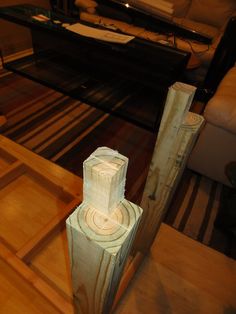 a wooden table topped with a sculpture on top of a hard wood floor next to a couch